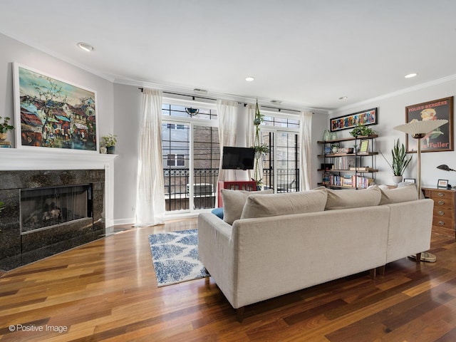 living room with a tiled fireplace, wood finished floors, and ornamental molding