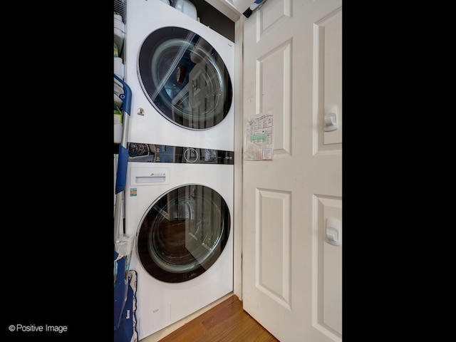 washroom featuring laundry area, wood finished floors, and stacked washing maching and dryer