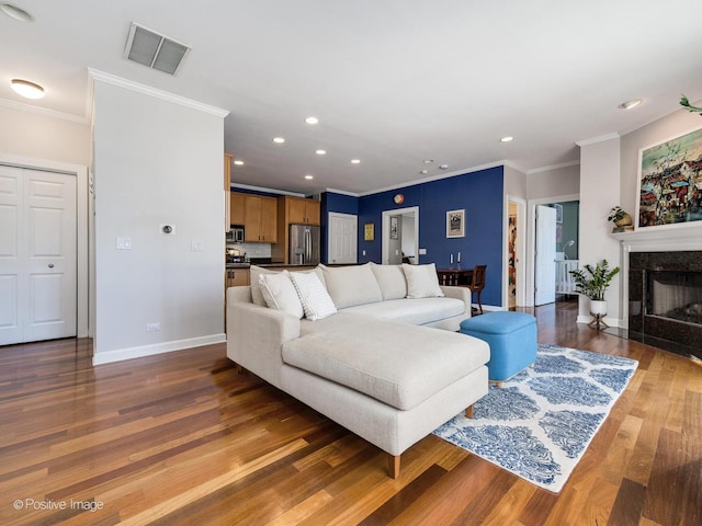 living room featuring visible vents, ornamental molding, wood finished floors, a premium fireplace, and baseboards