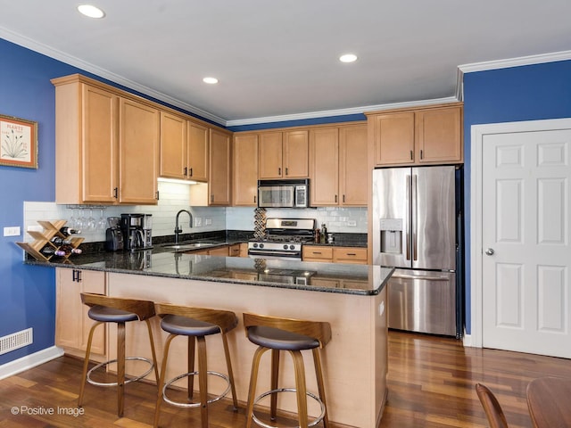 kitchen featuring dark stone countertops, ornamental molding, stainless steel appliances, and a sink