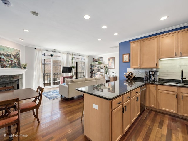 kitchen with a sink, backsplash, a tiled fireplace, ornamental molding, and dark wood-style flooring