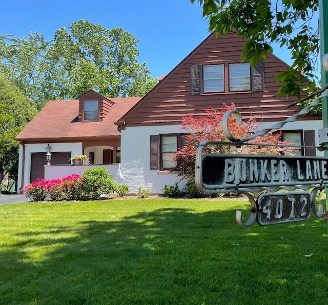 view of front of house with an attached garage, driveway, and a front lawn