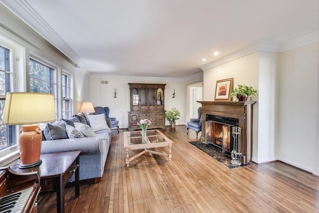 living room featuring a high end fireplace, visible vents, crown molding, and wood-type flooring