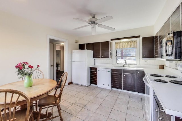 kitchen featuring a sink, tasteful backsplash, white appliances, light countertops, and light tile patterned floors