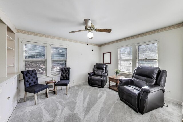 sitting room with a ceiling fan, light colored carpet, and baseboards