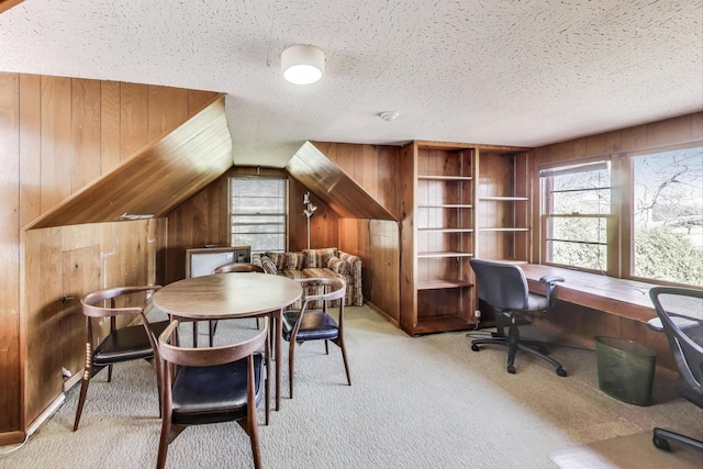 home office with light carpet, built in features, wood walls, and a textured ceiling