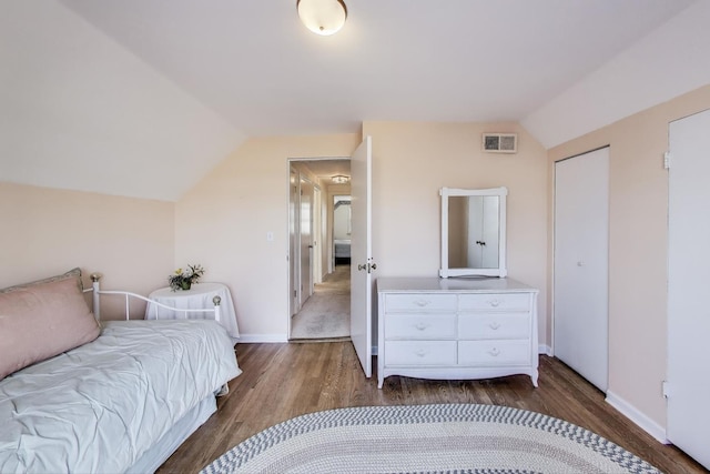 bedroom with lofted ceiling, wood finished floors, visible vents, and baseboards