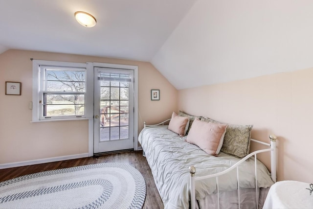 bedroom featuring access to exterior, baseboards, lofted ceiling, and wood finished floors