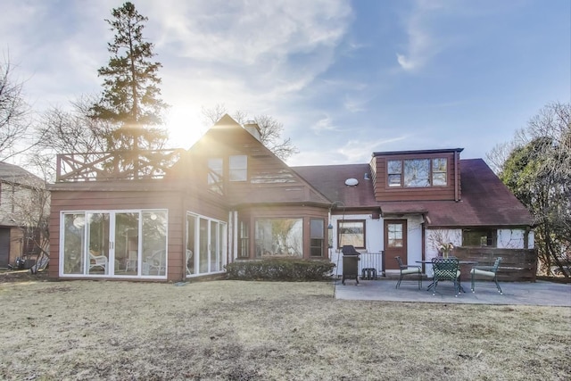 back of property with a lawn and a patio