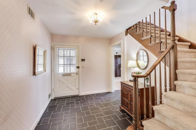 foyer entrance with visible vents, wallpapered walls, stairs, and baseboards