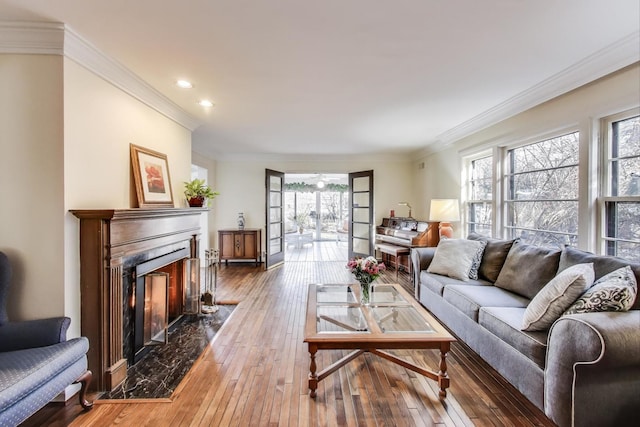 living area with ornamental molding, recessed lighting, wood-type flooring, and a premium fireplace