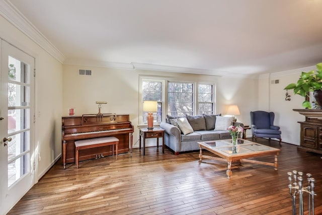 living room featuring visible vents, ornamental molding, and wood-type flooring