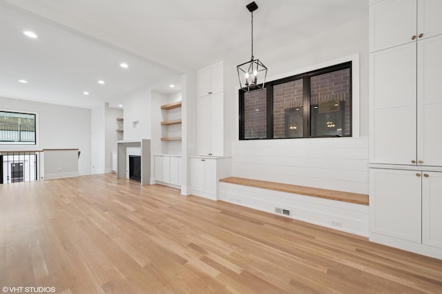 unfurnished living room with built in shelves, light wood finished floors, an inviting chandelier, recessed lighting, and a fireplace