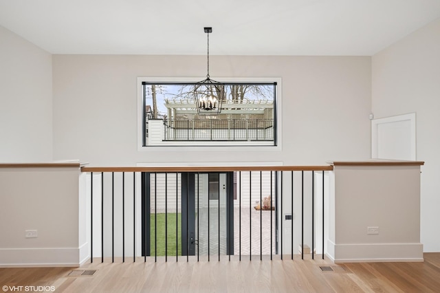 stairway with visible vents, baseboards, a notable chandelier, and wood finished floors