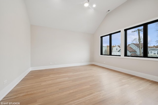 empty room with baseboards, lofted ceiling, and light wood finished floors