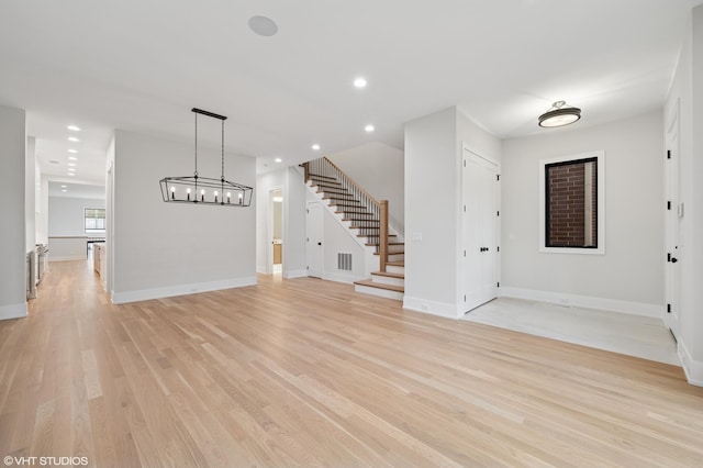 unfurnished living room featuring visible vents, baseboards, recessed lighting, stairs, and light wood-style floors