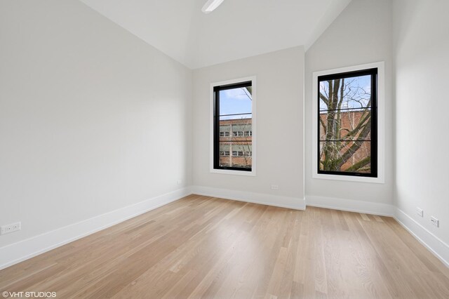 unfurnished room with baseboards, light wood-style floors, and vaulted ceiling