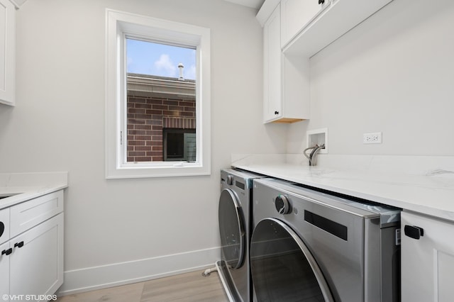 washroom featuring baseboards, cabinet space, light wood-style flooring, and washing machine and clothes dryer