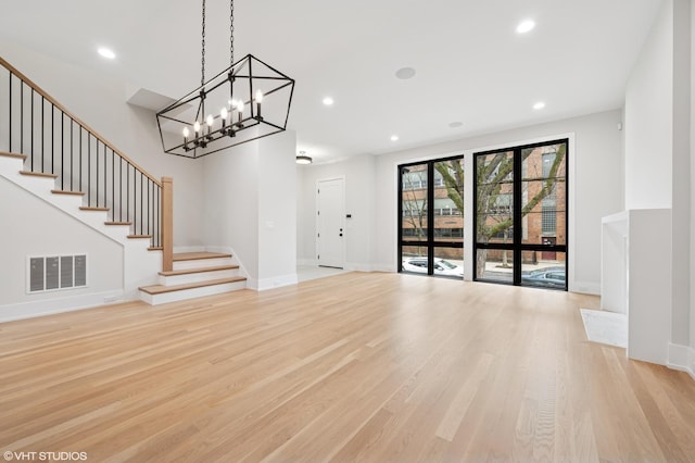 unfurnished living room with visible vents, baseboards, stairs, light wood-type flooring, and recessed lighting