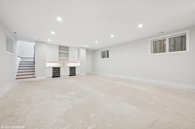 unfurnished living room with stairway, recessed lighting, beverage cooler, and concrete floors