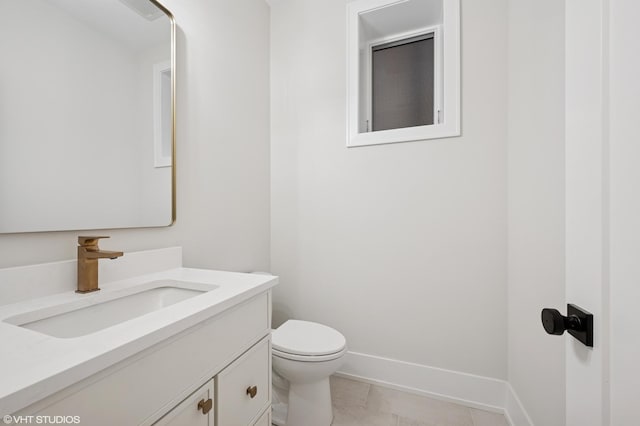 half bathroom with tile patterned floors, baseboards, toilet, and vanity