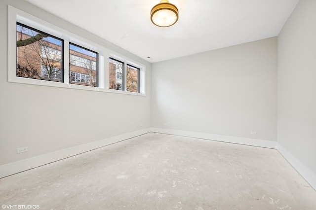 spare room featuring unfinished concrete flooring and baseboards