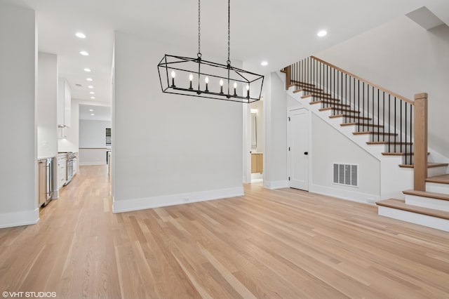 unfurnished dining area featuring visible vents, recessed lighting, light wood finished floors, baseboards, and stairs