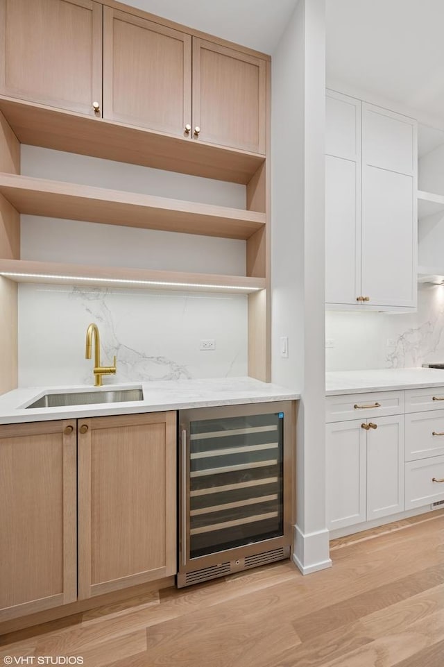 bar with decorative backsplash, wine cooler, light wood-style floors, and a sink