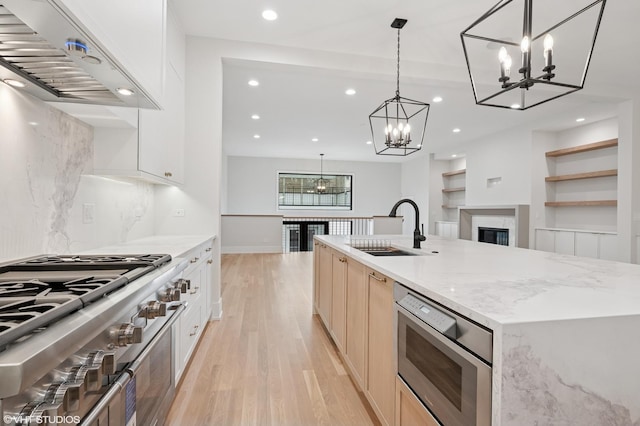 kitchen featuring stovetop, recessed lighting, a sink, exhaust hood, and light wood-type flooring