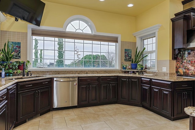 kitchen with a sink, stainless steel dishwasher, light tile patterned floors, decorative backsplash, and light stone countertops