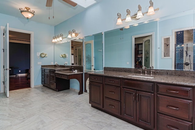 bathroom featuring a skylight, vanity, a walk in closet, and ceiling fan