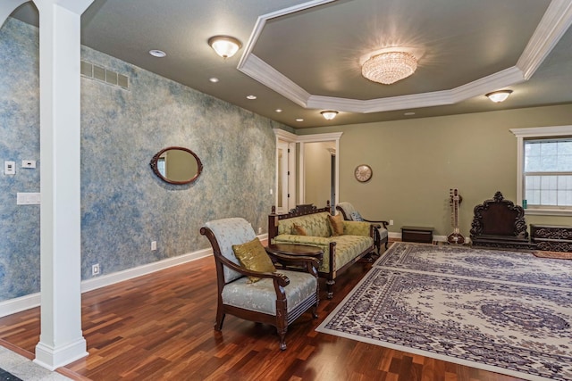 living room with visible vents, baseboards, ornamental molding, wood finished floors, and a raised ceiling