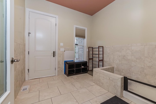 bathroom with tile patterned floors, visible vents, wainscoting, and tile walls