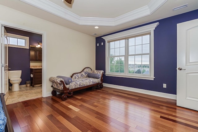 bedroom with crown molding, a raised ceiling, baseboards, and wood-type flooring