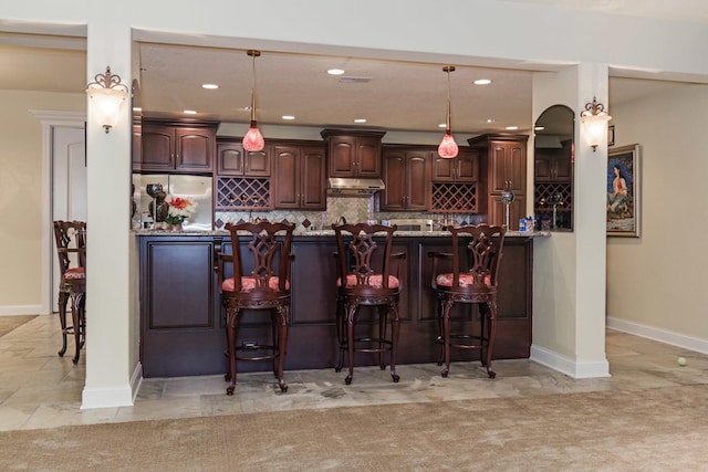 kitchen with dark brown cabinetry, a kitchen breakfast bar, freestanding refrigerator, and backsplash