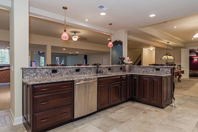 kitchen featuring light stone countertops, visible vents, a sink, stainless steel dishwasher, and open floor plan