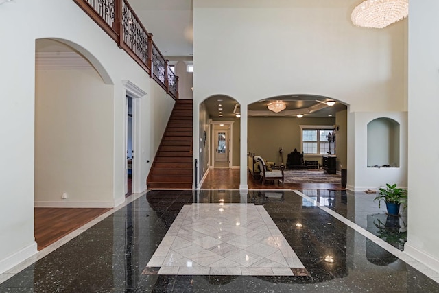 foyer entrance with a high ceiling, granite finish floor, arched walkways, and baseboards