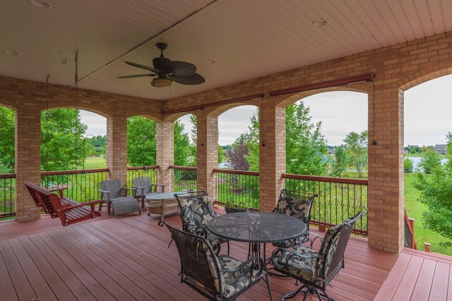 wooden terrace featuring outdoor dining area and a ceiling fan