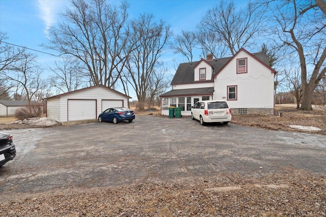 exterior space featuring a garage, an outbuilding, and a chimney