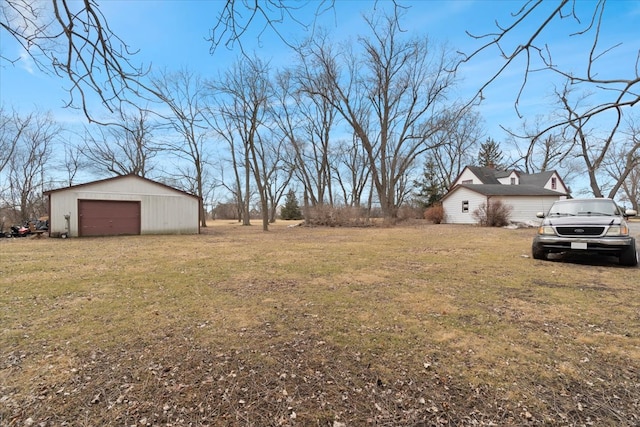 view of yard featuring a detached garage, driveway, and an outdoor structure