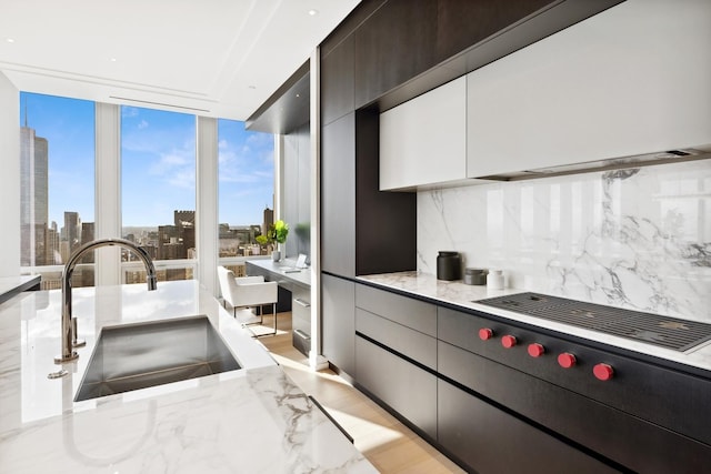 kitchen featuring a view of city, modern cabinets, a sink, a wall of windows, and decorative backsplash