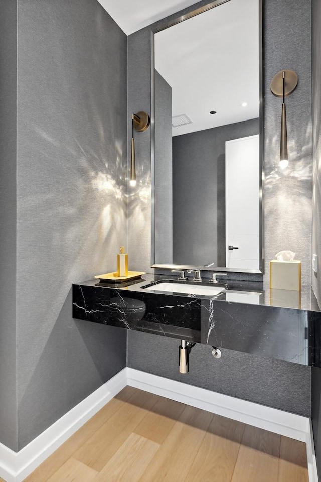 bathroom featuring wood finished floors, baseboards, and a sink