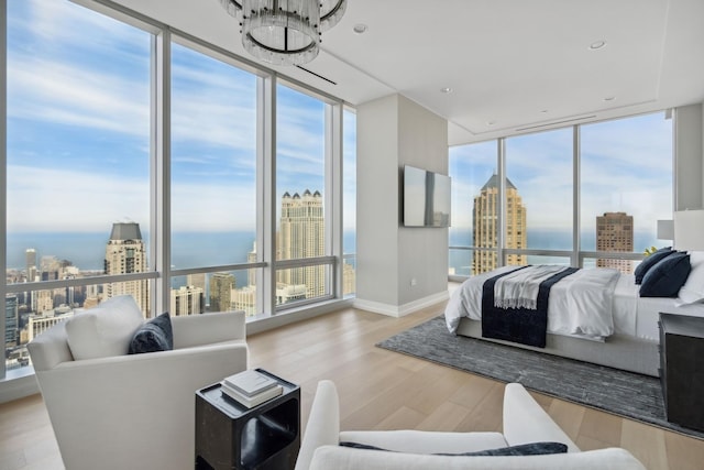 bedroom featuring multiple windows, a wall of windows, baseboards, and wood finished floors