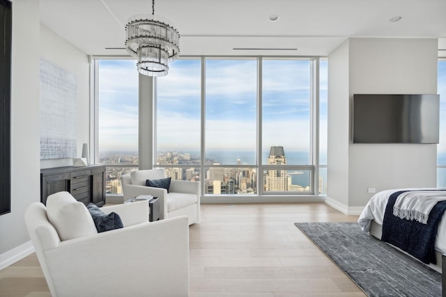 living area featuring expansive windows, baseboards, a notable chandelier, and wood finished floors