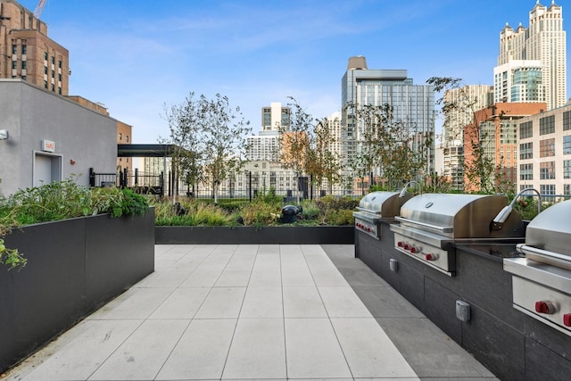 view of patio featuring grilling area, a city view, and exterior kitchen