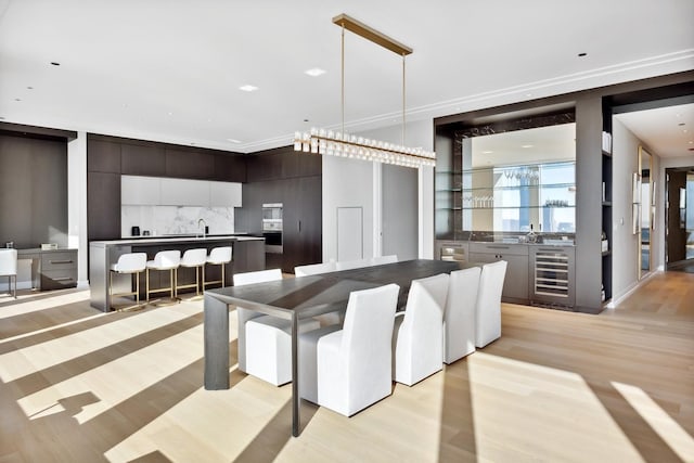 dining area with wine cooler, bar, and light wood-style flooring