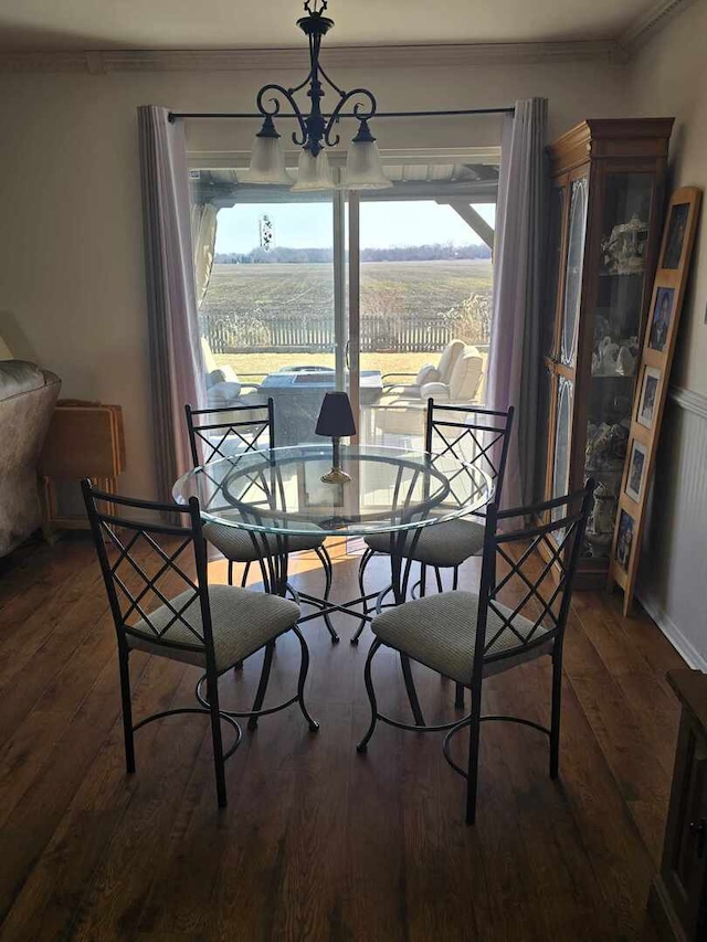 dining room featuring a rural view, an inviting chandelier, wood finished floors, and ornamental molding