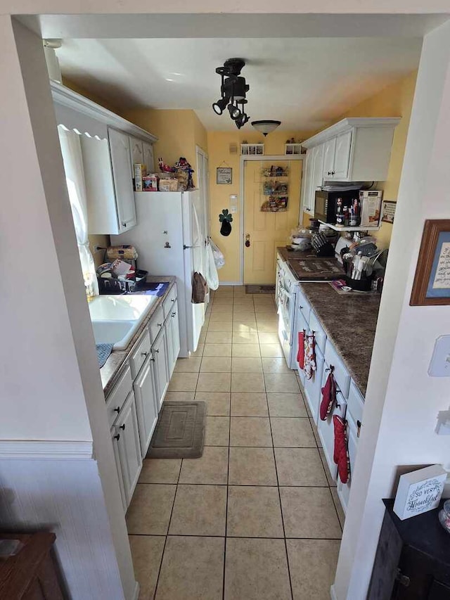 kitchen with light tile patterned flooring, white cabinetry, and dark countertops