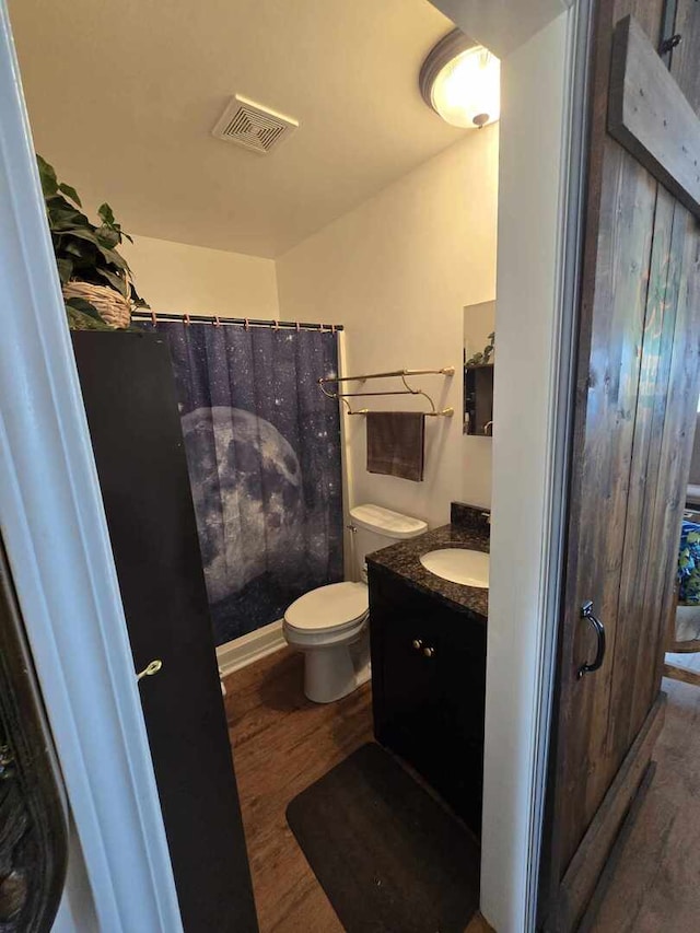 full bathroom featuring visible vents, toilet, a shower with shower curtain, wood finished floors, and vanity