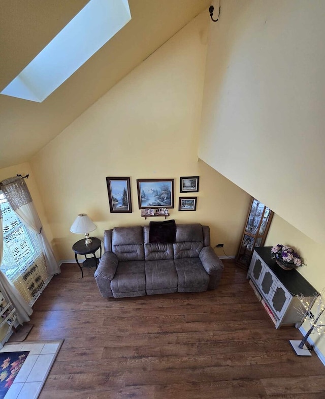 living area featuring high vaulted ceiling, a skylight, and wood finished floors